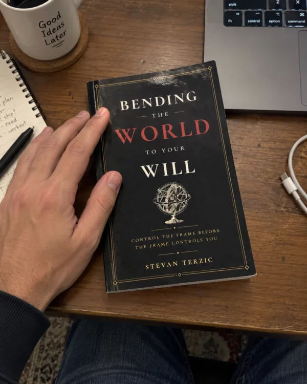 A hand resting on Bending the World to Your Will on a wooden desk